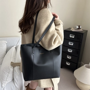 Minimalist black leather tote bag for women shown as a stylish shoulder bag on a model