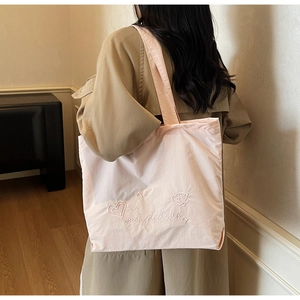 Close-up of light pink tote bag with embroidered stars and hearts on a casual model