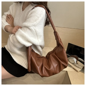 Détail d'un sac dumpling marron plissé en similicuir texturé porté à l'épaule pour femme