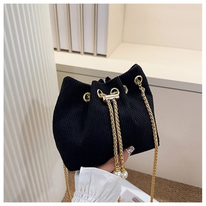 Détail du sac seau en velours côtelé noir avec chaîne dorée et accents de perles de serrage