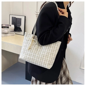 Detail der weißen Tweed-Tasche mit Perlen-Schleifen-Anhänger und Leder-Schultergurt