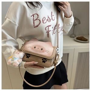 Detail of cartoon cat shoulder bag in pink and brown PU leather with plush charm