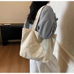 Detail shot of beige canvas tote bag featuring premium heart and star embroidery texture