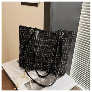 Nahaufnahme der schwarzen Tweed-Tasche mit Goldwebmuster und edlen Ledergriffen