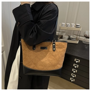 Detail of vintage quilted tote bag with brown suede and black leather stitching