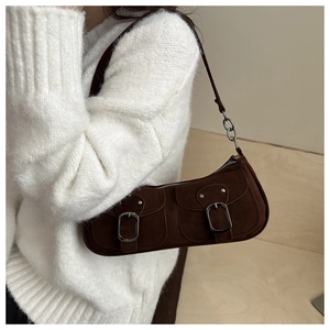 Gros plan sur le sac sous le bras en daim marron foncé avec poches à boucles métal