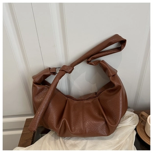 Détail de la texture cuir PU marron grainé litchi sur un sac à bandoulière plissé en lune