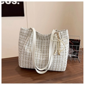 Détail d'un sac cabas en tweed blanc avec pendentif nœud en perles et anses en cuir