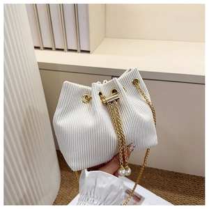 Détail du sac seau en velours côtelé blanc avec chaîne dorée et perle de cordon