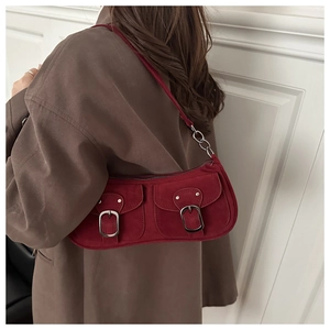 Détail du sac sous le bras en daim rouge avec boucles argentées et bandoulière chaîne
