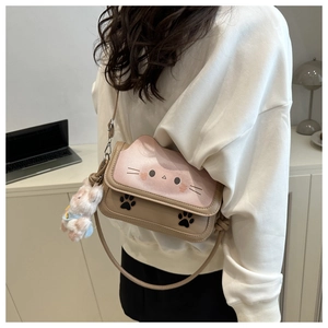 Detail of cute cat crossbody bag with plush rabbit charm and elegant shoulder strap knot