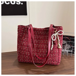 Détail d'un cabas en tweed rouge foncé avec fils dorés et breloque noeud en perles