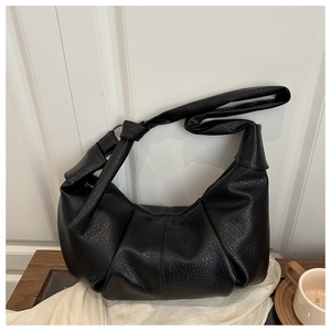 Détail du sac hobo en cuir noir avec texture litchi et plis sur tissu en soie