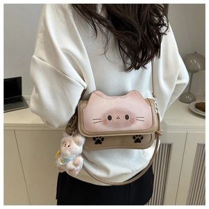 Detail of pink cat-shaped crossbody bag with animal prints and plush bear pendant