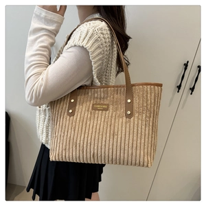 Detail of khaki corduroy tote bag with brown leather handles and brand logo