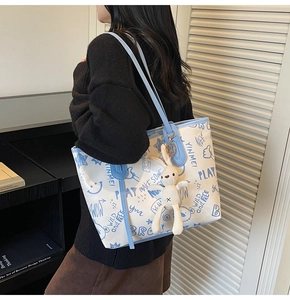 Détail d'un grand sac cabas blanc avec imprimés graffiti bleus et charmant lapin en peluche