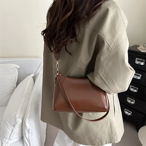 Sac bandoulière minimaliste en cuir marron au style vintage, porté par un mannequin