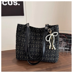 Détail du sac cabas en tweed noir avec fils dorés et charm nœud en perles