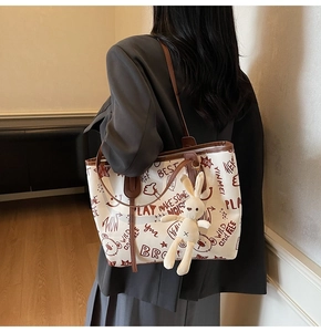 Détail du sac cabas en toile blanche avec anses en cuir brun et imprimé graffiti