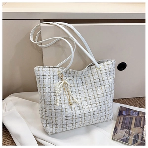 Detail der weißen Tweed-Tasche mit Goldfäden und einem Perlen-Schleifen-Anhänger