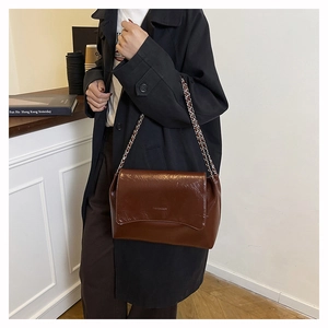 Brown vintage faux leather tote bag with silver chain strap shown in a street style view