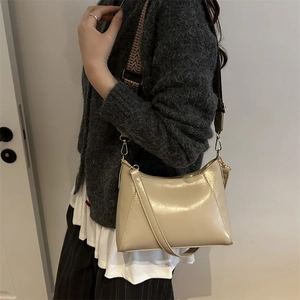 Sac bandoulière beige minimaliste en similicuir texturé porté par un mannequin