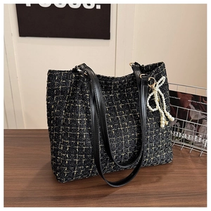 Détail du sac cabas en tweed avec touches jaunes et pendentif nœud en perles élégant