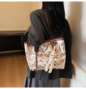 Détail du sac cabas imprimé avec des motifs graffiti et un charmant pendentif lapin