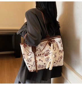 Vue détaillée du sac cabas blanc graffiti avec anses en cuir marron et breloque lapin