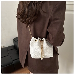 Detailed shot of white mini bucket bag with woven texture and gold chain strap