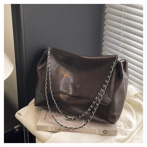 Macro detail of glossy oil wax leather tote with silver chain strap and flip cover