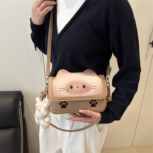 Cute cat-themed beige crossbody bag with plush charm and feline paw prints on PU leather