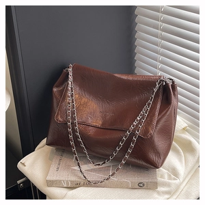 Detail of retro brown embossed leather tote with elegant silver chain strap texture