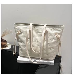 Detail of off-white tote bag featuring embossed bow patterns and adjustable side drawstrings
