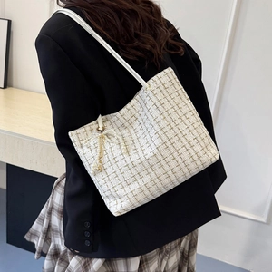 Weiße Tweed-Schultertasche mit Perlen-Bogen-Anhänger, getragen von einem Modell im Trend