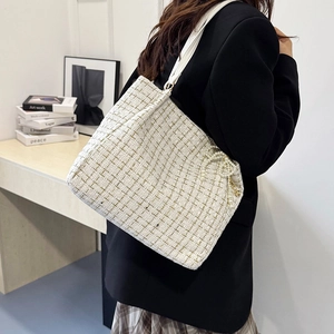 Sac sous le bras élégant en tweed écru avec fil doré et charm nœud perlé porté par mannequin