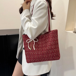 Elegante rote Schultertasche aus Tweed mit Perlen-Schleife und Gold-Anhänger an einem Model