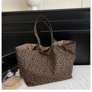 Detail of a large leopard print fabric tote bag with dual handles in a modern setting