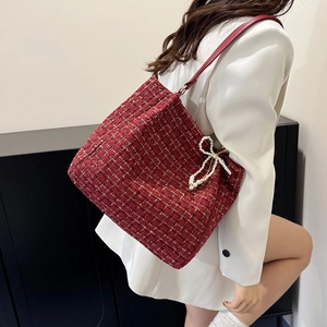Sac fourre-tout en tweed rouge avec texture dorée et breloque noeud en perles en shooting