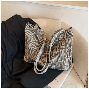 Dettaglio borsa tote jacquard boho con tracolla decorata su un divano bianco morbido
