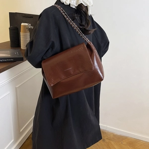 Vintage glossy dark brown tote bag with metal chain strap shown on a model back view
