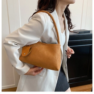 Détail du sac à bandoulière en daim camel avec mini pochette décorative sur le côté
