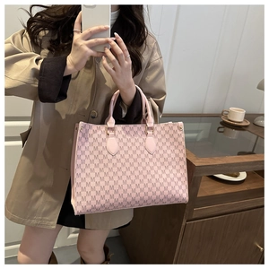 Close-up of pink tote bag with M-pattern monogram print and matching leather handles