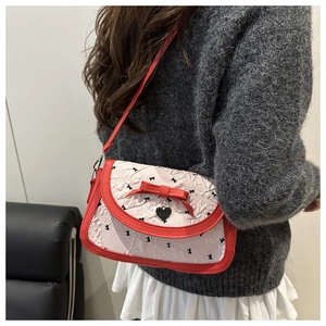 Detail of pink pleated crossbody bag with red leather trim and black bow heart charm