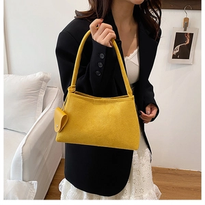 Détail d'un sac bandoulière jaune minimaliste avec petit accessoire rond assorti