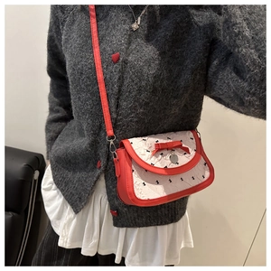 Detail of red and white crossbody bag with bow prints and heart metal pendant charm