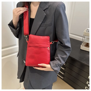 Detail of red pebbled leather crossbody bag with wide canvas strap on model