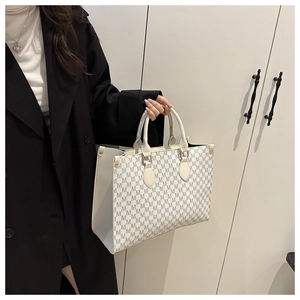 Detail of luxury letter pattern tote bag with gold hardware and ivory handles