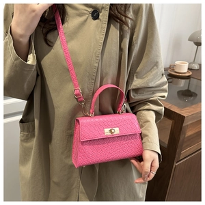 Detail of hot pink woven texture handbag with golden twist lock on a beige coat