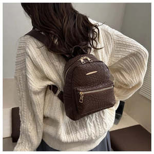 Détail d'un mini sac à dos marron tressé montrant la texture et les ferrures dorées